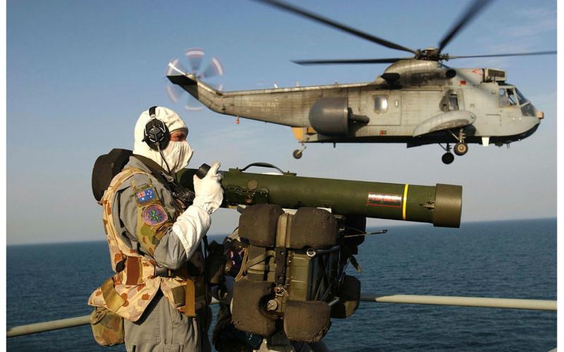 A member of the 16th Air Defence Regiment attached to HMAS Kanimbla as a Coalition Sea King passes by, March 2003. 
