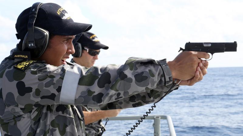 Seaman Boatswains Mate Thomas Fujii fires the 9mm Hi-power pistol onboard HMAS Bathurst.