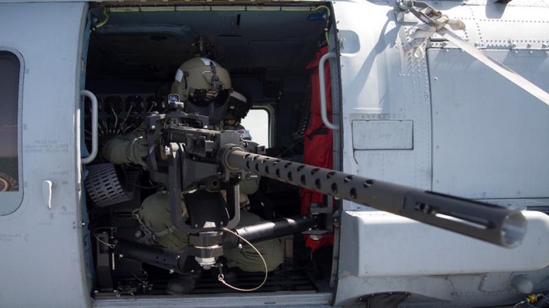 POA Chris Hodgkinson tests and adjusts the 12.7mm mounted machine gun before taking off in HMAS Perth’s embarked MH-60R helicopter to do a live firing exercise off the coast of Western Australia.