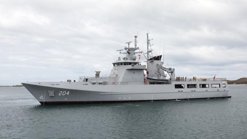 A grey ship in calm water on an overcast day.