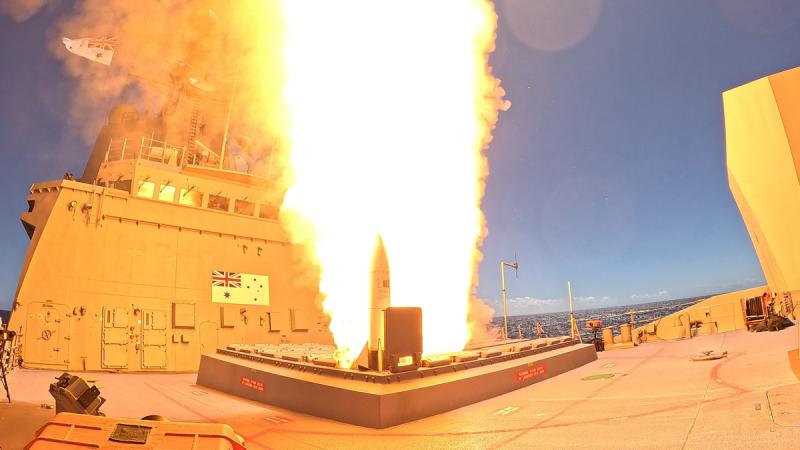 Missile firing on Navy ship out at sea. Blazing fire and smoke around the missile.